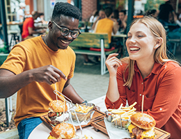 two young adults eating burgers